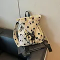 Mochila de lona con lunares para mujer sobre un libro de diseño moderno - Caqui