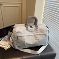 Detail view of a grey travel duffle bag with embroidered logo and textured design elements. - Gray