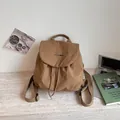 Vue détaillée d'un sac à dos marron léger avec logo sur une surface texturée - Khaki