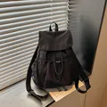 Primer plano de mochila negra con cordón, logotipo bordado y solapa - Negro
