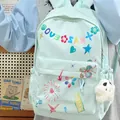 Close-up of mint green backpack with colorful graffiti prints and cute ghost plush charm. - Green