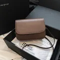 Gros plan d'un sac à bandoulière carré marron rétro dans une boîte cadeau noire élégante - Café