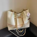 Stylish summer woven tote bag with elegant stripes and a cute plush monster charm - Khaki
