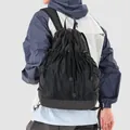 Back view of stylish black grid drawstring backpack worn with an outdoor jacket - Black