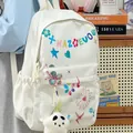 Close-up detail of white fashion backpack with colorful doodles and plush panda charm - White