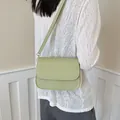 Back view of a stylish minimalist sage green square crossbody bag worn with a white top. - Green