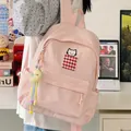 Detail view of a pink backpack with cat embroidery and a moon charm in a cozy room. - With Charm / Pink