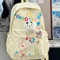Close-up of stylish cream backpack featuring colorful prints and a fluffy star charm. - Yellow