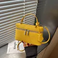 Detailed view of a bright yellow textured mini box bag featuring a top handle and shoulder strap. - Yellow