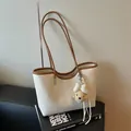 Detailed view of cream and brown minimalist tote bag with cute bear charm - With Charm / Off White