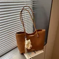 Brown textured tote bag featuring a cute plush dog charm and minimalist design details. - With Charm / Brown