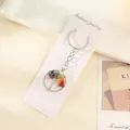 Handgefertigter Lebensbaum Schlüsselanhänger mit sieben Chakra Naturkristallen auf weißer Karte. - Rund Silber / 3cm