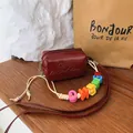 Detailed view of mini burgundy crossbody bag featuring colorful alphabet bead strap design - Red
