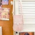 Primo piano di una borsa a tracolla rosa per cellulare appesa a una porta bianca - Rosa