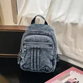 Detailed view of a trendy washed denim backpack with multi-zipper compartments - Dark Blue