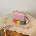 Detail of a pink mini crossbody bag with colorful alphabet beads on a yellow cord. - Pink
