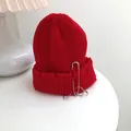 Detail view of red knit beanie featuring hip-hop rings, large safety pin, and distressed edges. - 55-58cm (Elastic) / Red