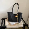 Close-up of black woven leather tote bag with stylish tassel charm detail - With Pendant / Black