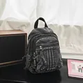 Close-up of vintage black denim backpack on a desk next to a stylish retro speaker - Black