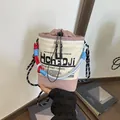 Nahaufnahme einer modischen Canvas-Beuteltasche mit bunten Seilen und markantem Buchstabendruck. - Rosa