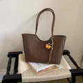 Detailed view of a brown woven tote bag with floral charm on a styled chair - With Pendant / Brown