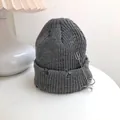 Close-up detail of a grey knitted beanie featuring silver safety pin and ring accents. - 55-58cm (Elastic) / Gray