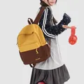 Model wearing a stylish yellow and brown preppy style backpack for school or travel - With Charm / Yellow