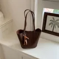 Retro dark brown woven bucket bag featuring a beaded charm and decorative wavy top edge. - With Pendant / Brown