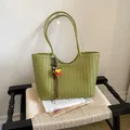 Green woven underarm tote bag for summer, styled in a minimalist lifestyle setting - With Pendant / Green