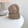 Detail of a beige ribbed knit beanie with silver safety pin and ring accents. - 55-58cm (Elastic) / Beige