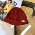 Detailed macro view of children reddish-brown knitted beanie with PPSW white label - 3 Years+ to Adult / Burgundy