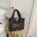 Bolso tote grande de lona gris oscuro con bordado naranja MORE RICH & MORE en habitación - Marrón Oscuro