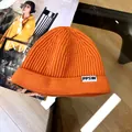 Close-up of vibrant orange ribbed knit kids' beanie featuring a PPSW decorative patch - 3 Years+ to Adult / Orange