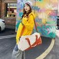 Stylish cream and orange canvas duffel bag carried by a woman against a graffiti wall. - With Label / Orange (With Logo)