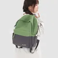 Detailed macro view of a stylish two-tone green and grey casual backpack worn by a female model - With Charm / Green