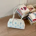Bolso de hombro vintage blanco con lunares azules en una escena de estilo de vida con libros - Lunares Azules