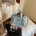 Close-up of light blue denim bucket bag with silver rivet patterns and star charms - Style 2 Blue With Charms