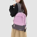 Female student wearing a stylish pink and gray color-block backpack in college style - With Charm / Pink