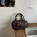 Primer plano de un elegante bolso tejido marrón sobre una encimera de madera de estilo rústico - Café