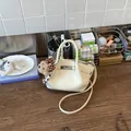 Detailed close-up of a cream white wrinkled leather bucket bag featuring a cute teddy bear charm - With Pendant / White