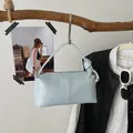 Detailed shot of a light blue vintage pillow bag hanging on a rustic wooden branch. - Blue