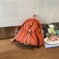 Foto de estilo de vida de una mochila abullonada terracota única en una mesa de madera rústica - Naranja