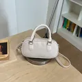 Vista detallada del bolso de mano trenzado en color crema con herrajes plateados - Blanco
