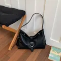 Black faux leather hobo shoulder bag with silver buckle detail in a room setting - Black