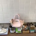 Detailed lifestyle shot of a light pink glossy bucket bag with a cute bear charm on a vanity - With Pendant / Pink