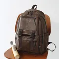 Mochila vintage de cuero marrón presentada en una silla de madera con bate de béisbol - Marrón