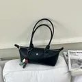 Gros plan d'un sac à main noir minimaliste avec breloque perlée colorée sur un coussin - Avec Pendentif / Noir