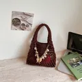 Λεπτομερής προβολή καφέ πλεκτής τσάντας με διακοσμητική αλυσίδα κοχυλιών και μαργαριταριών - Καφέ