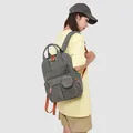 Vista lateral de una mochila de viaje gris impermeable con detalles naranjas en un modelo - Estilo Pareja (Con Bolsa) / Gris Niebla