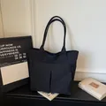 Minimalist black large capacity fabric tote bag for commuting and students on a desk - Black